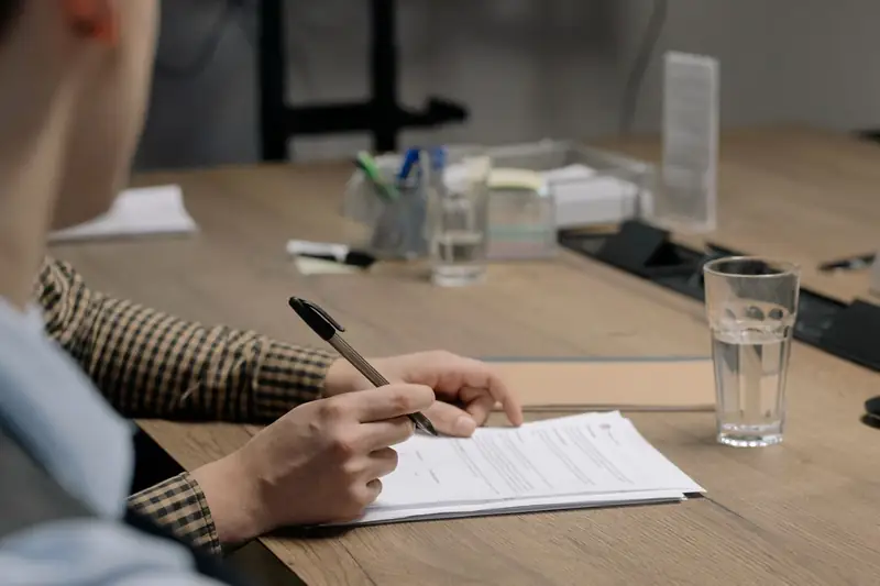 A professional reviews and marks up a printed document at a conference table