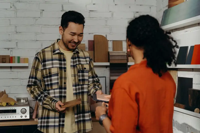 A shop owner walks a customer through wood samples at a showroom counter
